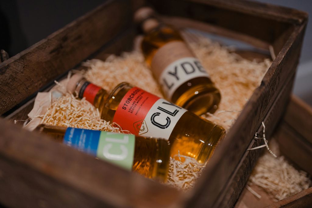 짚으로 채워진 나무 상자에 담긴 3병의 술은 다채로운 라벨과 코르크 상판을 선보입니다.