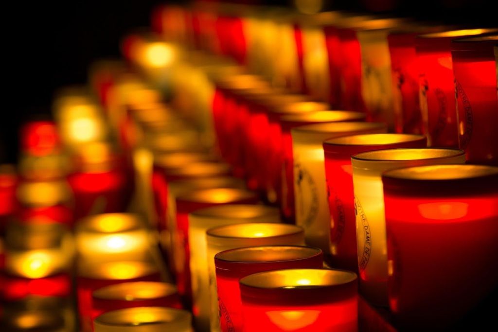 어둠 속에서 빛나는 빨간색과 흰색 촛불이 줄지어 있습니다.