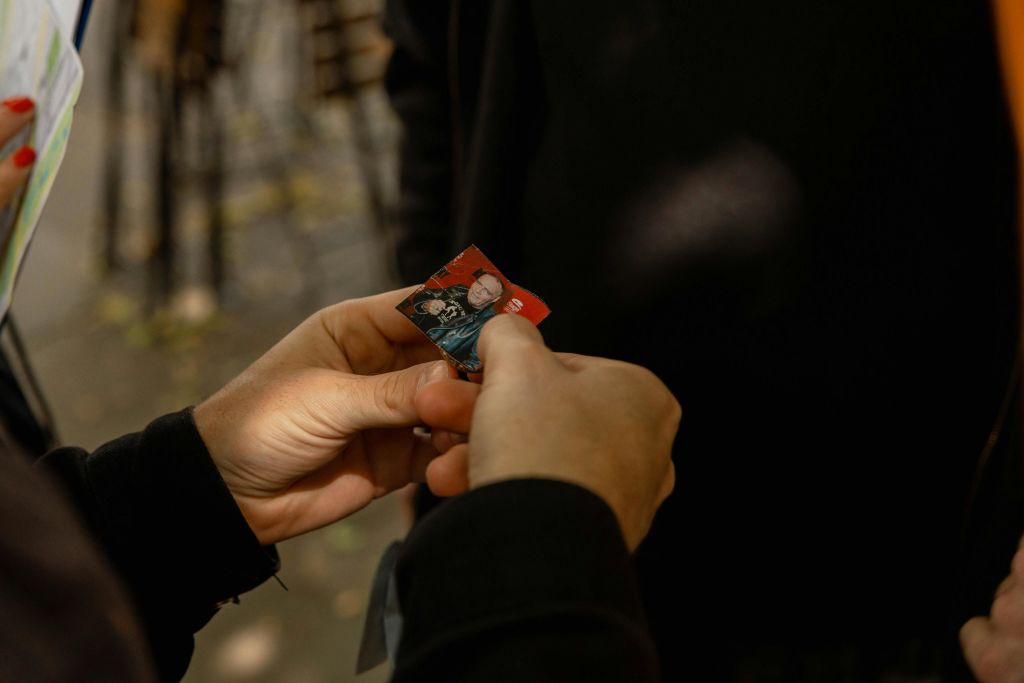 야외 배경이 흐릿한 작은 사진을 손에 들고 검사하는 사람과 다른 사람.