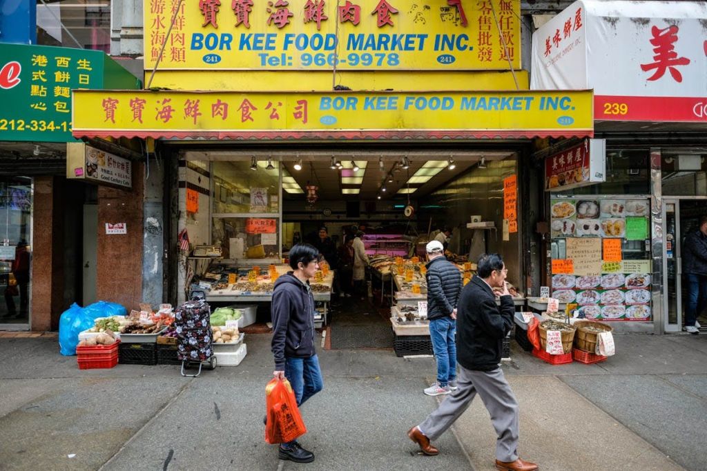 다양한 식품을 판매하는 밝은 색상의 매장인 Bor Kee Food Market Inc. 의 입구를 지나면 사람들이 걸어옵니다.