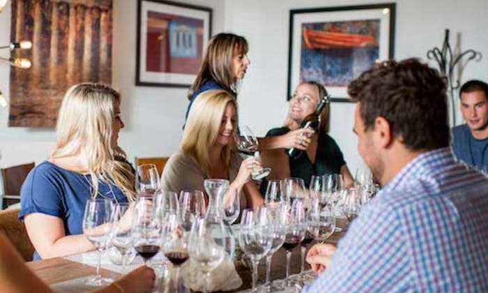 와인잔이 놓인 테이블에 둘러앉은 사람들 중 일부는 캐주얼하고 실내적인 분위기에서 와인을 붓는 여성에 의해 채워졌습니다.