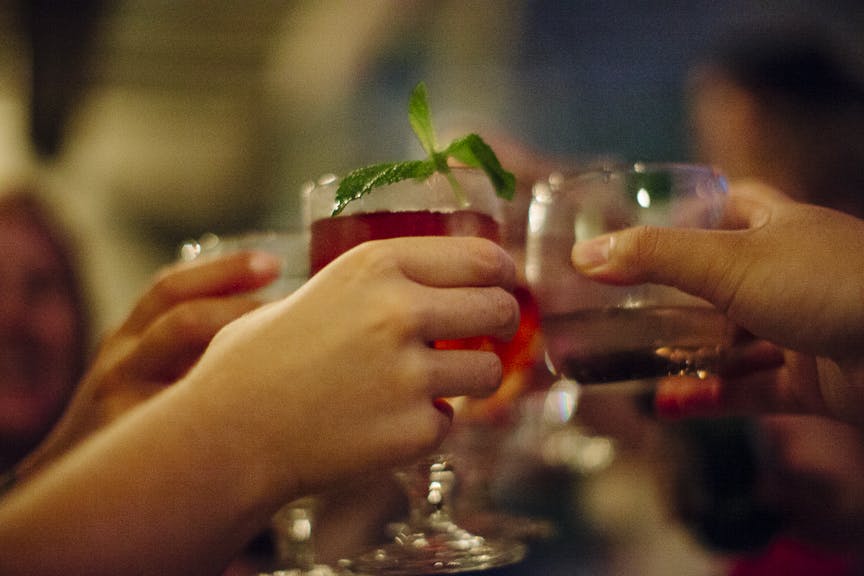 토스트에 음료수 잔을 올리는 손이 여러 개 있고, 한 잔에는 민트 장식이 있습니다.