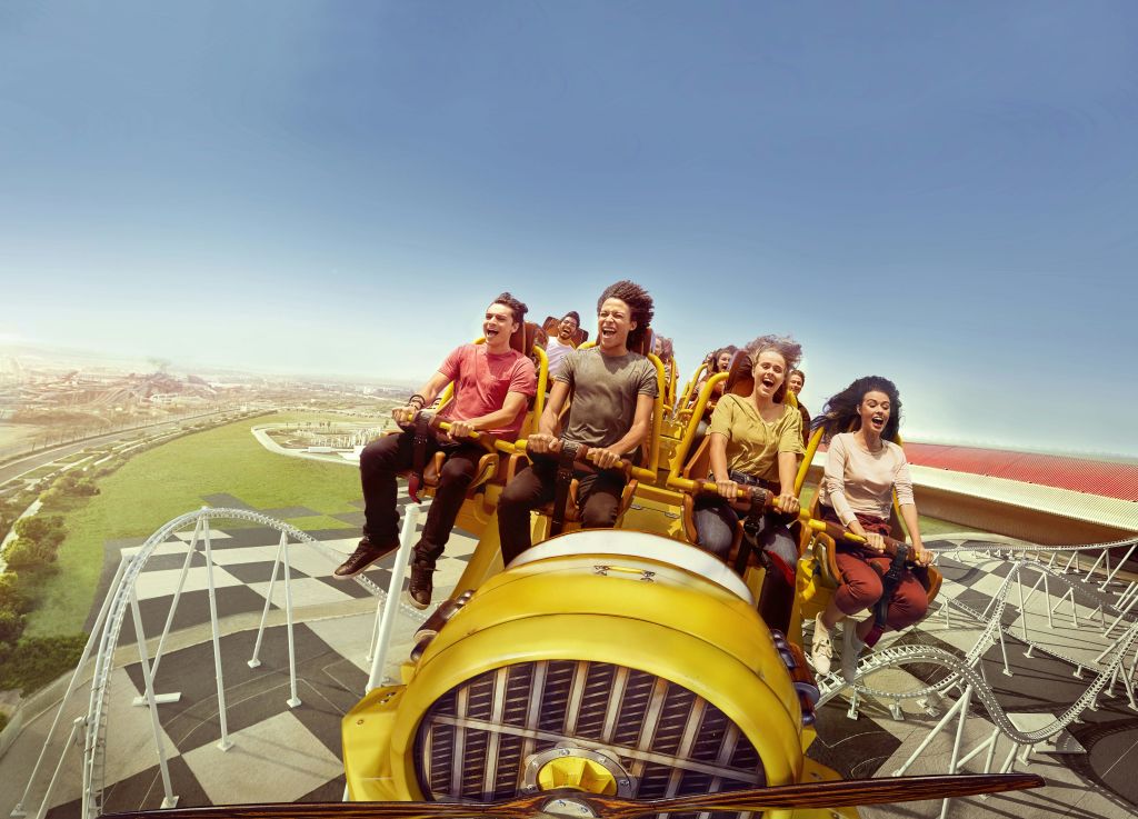 맑고 푸른 하늘 아래 노란색 롤러코스터를 타고 즐거운 비명을 지르는 사람들.