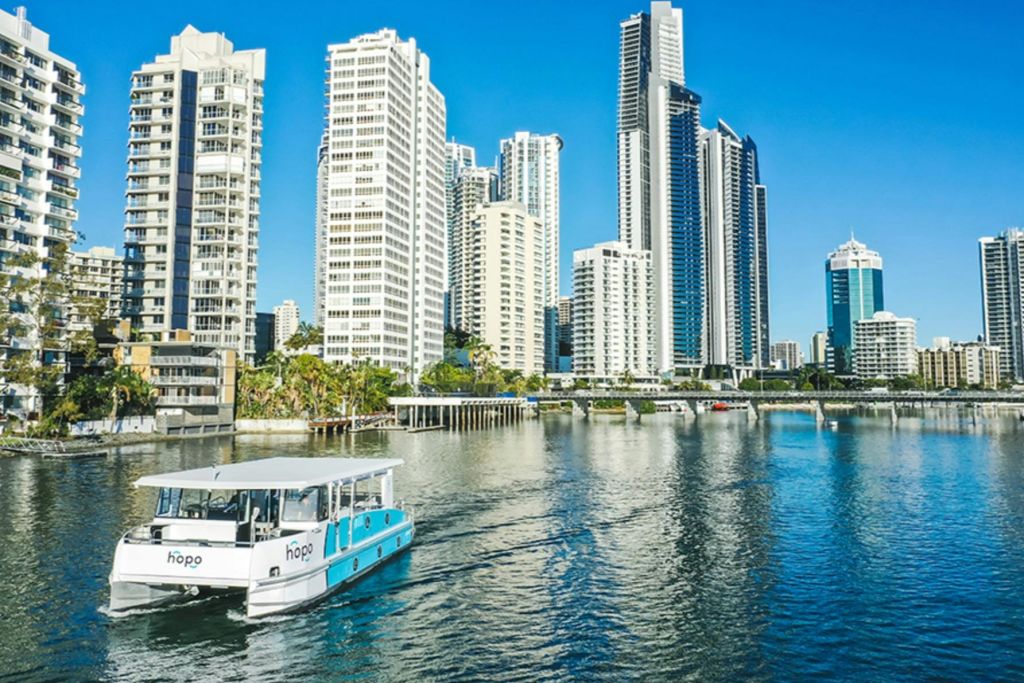 강가의 현대적인 높은 건물이 있는 도시 스카이라인으로, 전경의 물가에 '호포' 라고 적힌 작은 페리가 있습니다.