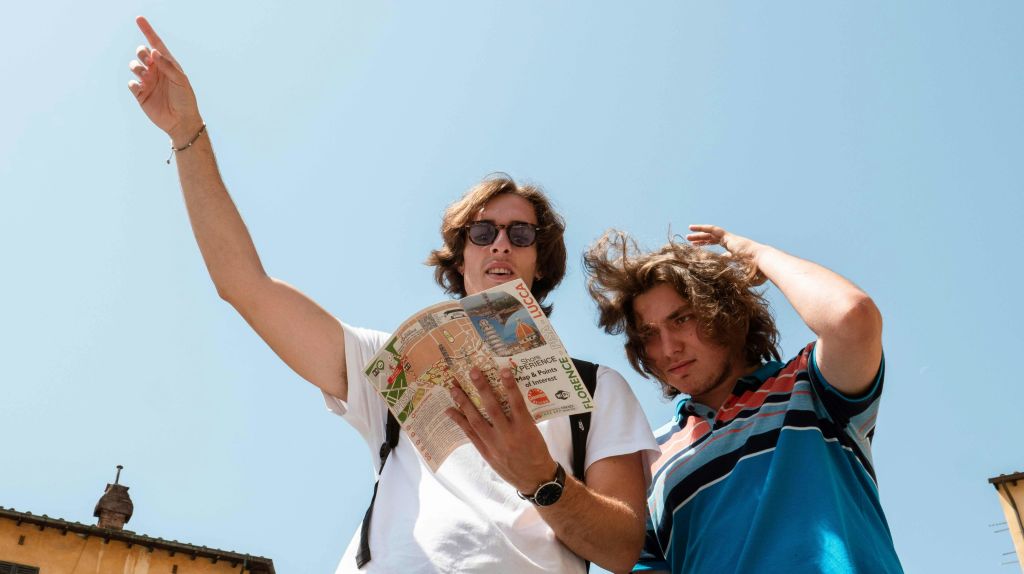 야외에서 선글라스를 끼고 지도를 들고 있는 두 사람이 맑고 푸른 하늘 아래를 둘러보고 있습니다.