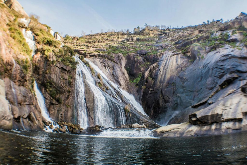 여러 개의 폭포가 바위 절벽을 따라 맑은 하늘 아래 잔잔한 물줄기로 이어집니다.