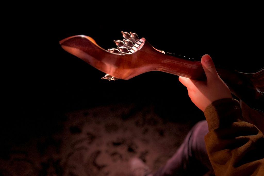 희미한 조명 속에서 기타의 목을 잡고 있는 손.