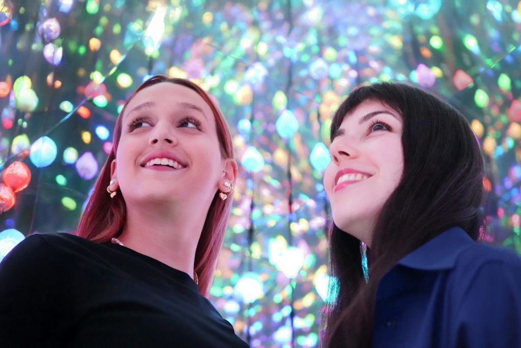 보케 효과를 배경으로 화려하고 빛나는 조명 디스플레이를 바라보며 미소 짓는 두 사람.