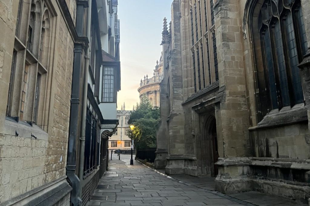 역사적인 건물 사이의 좁은 돌 포장 골목은 화려한 디테일을 배경으로 한 원형 구조로 이어집니다.