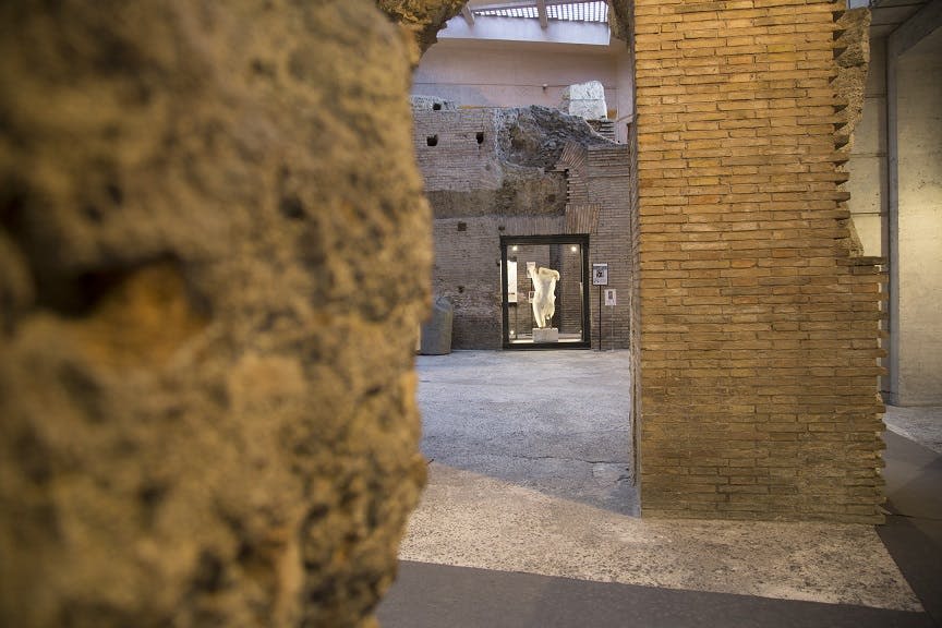 마당 유리 케이스에 전시된 흰색 동상의 고대 벽돌 유적을 감상할 수 있습니다.