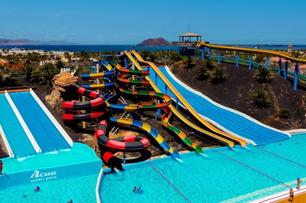 여러 개의 슬라이드가 수영장으로 이어지는 다채로운 워터파크는 맑고 푸른 하늘 아래 경치 좋은 풍경으로 둘러싸여 있습니다.