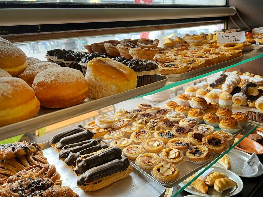 제과점의 금속 및 유리 선반에 진열된 에클레어, 타르트, 도넛 등 다양한 페이스트리.