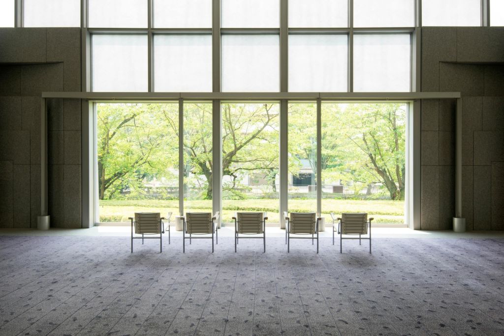 커다란 창문 앞에 6개의 의자가 나란히 놓여 있어 푸른 나무와 정원을 한눈에 조망할 수 있습니다.