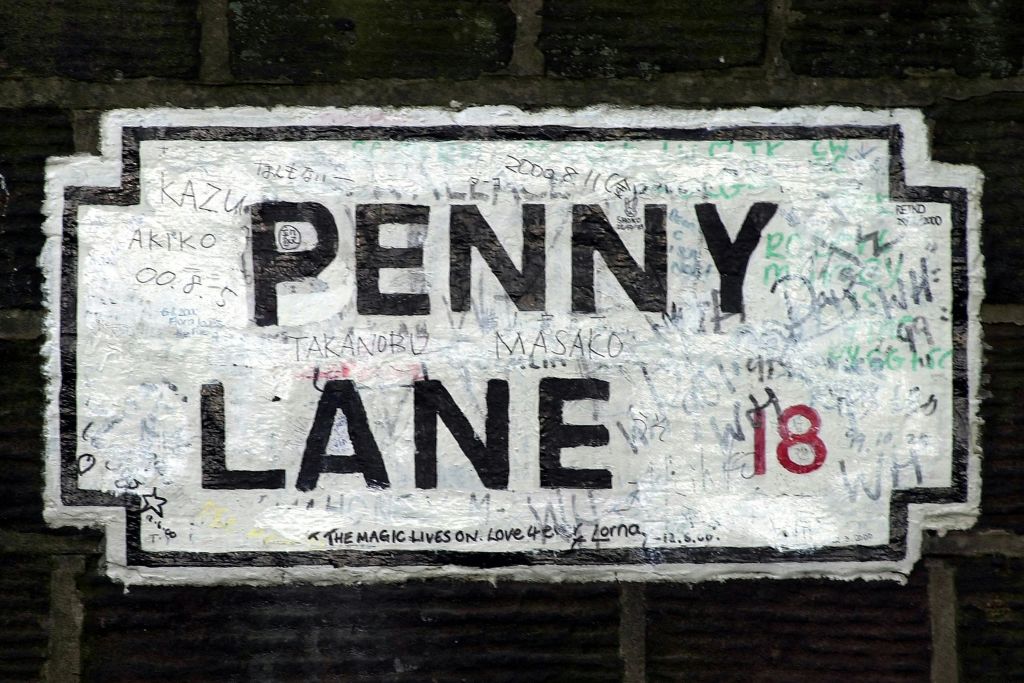 페니레인 (Penny Lane) 을 읽는 풍화된 거리 표지판에 낙서와 메시지가 적혀 있습니다. 숫자 "18" 은 빨간색입니다.