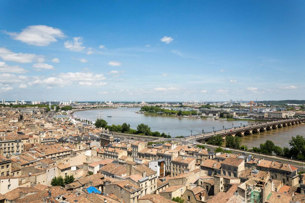 맑고 푸른 하늘 아래 빽빽한 건물과 강, 돌다리가 있는 도시의 공중 전망.