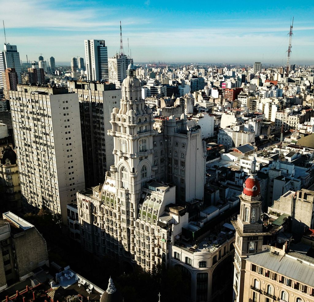 전경에 돔이 있고 푸른 하늘 아래 배경에 현대적인 고층 건물이 있는 역사적이고 화려한 건물이 있는 도시 풍경.