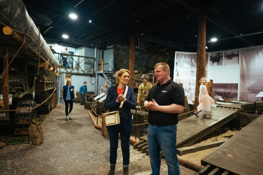 Museum visitors with guide in exhibition with W.W.II Military vehicles in War Museum Medemblik in the Netherlands