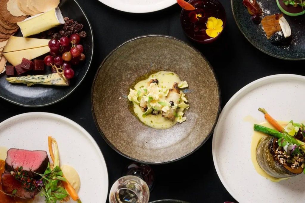 도금 음식이 담긴 중앙 그릇과 다양한 재료가 담긴 주변 접시를 포함한 다양한 고급 요리가 놓인 테이블입니다.