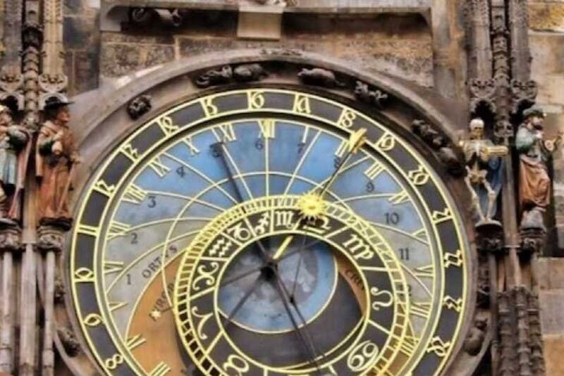 역사적인 건물 외관에 화려한 다이얼과 디테일한 조각이 있는 화려한 천문 시계의 클로즈업.