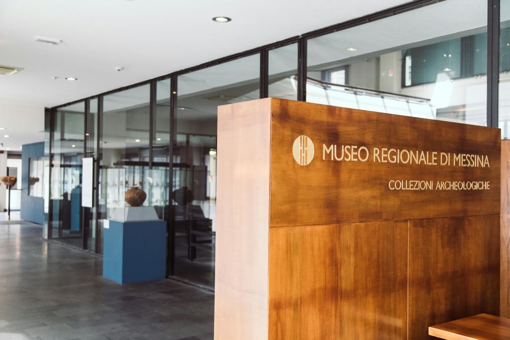 "Museo Regional" 이라고 적힌 나무 간판과 유리 진열장을 배경으로 한 박물관 내부.