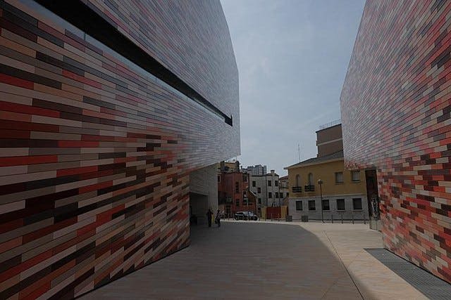 양쪽에 화려한 모자이크 타일 건물이 있는 좁은 거리를 배경으로 더 전통적인 건물이 나옵니다.