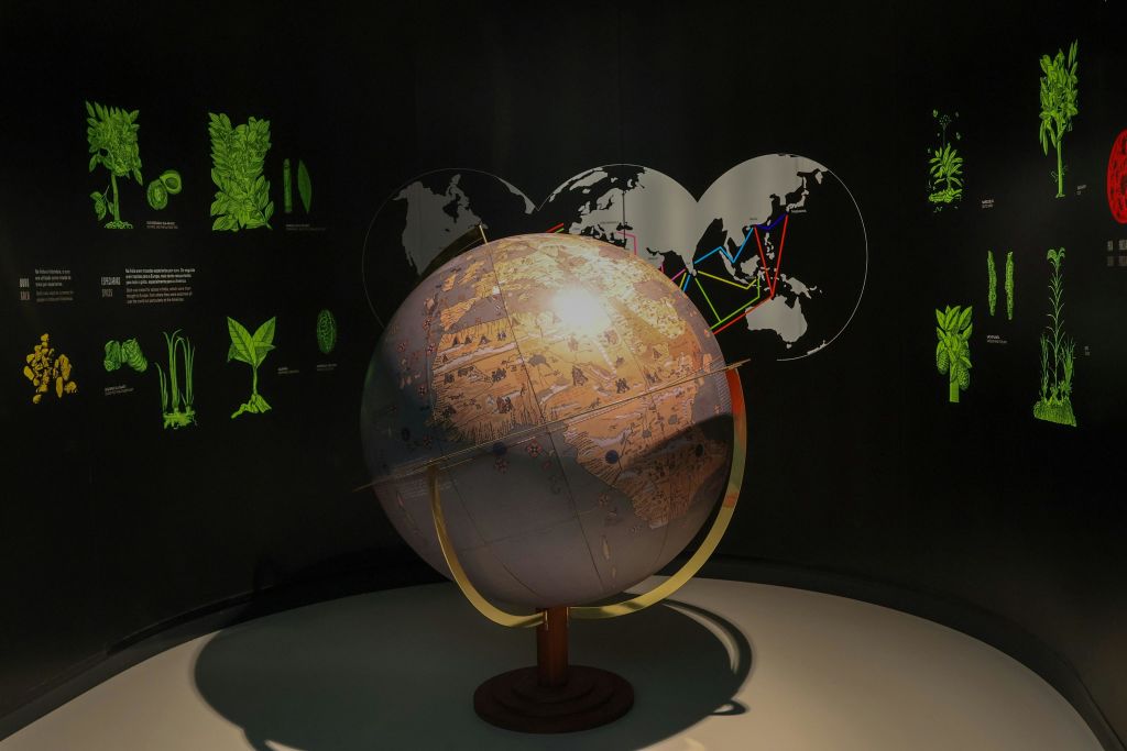 주변 벽에 조명이 켜진 지도와 도표가 있는 조명이 희미한 방에 표시된 지구본입니다.