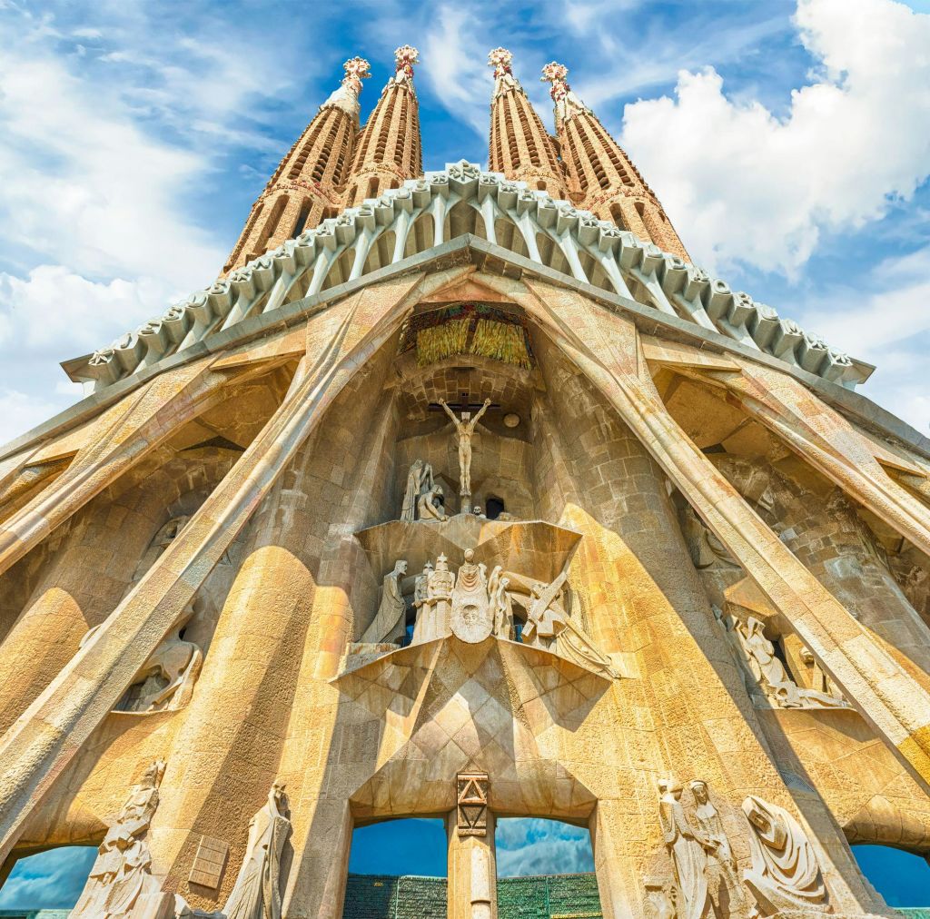 사그라다 파밀리아 (Sagrada Familia) 의 정교한 외관 아래에서 내려다보는 전망은 섬세한 조각품과 탁한 푸른 하늘을 배경으로 한 높은 첨탑을 갖추고 있습니다.