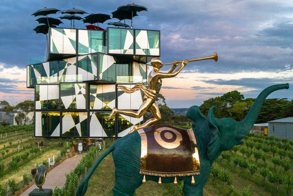 장식된 코끼리를 타고 나팔을 부는 사람의 금상 뒤에 있는 기하학적 디자인의 현대적인 건물.