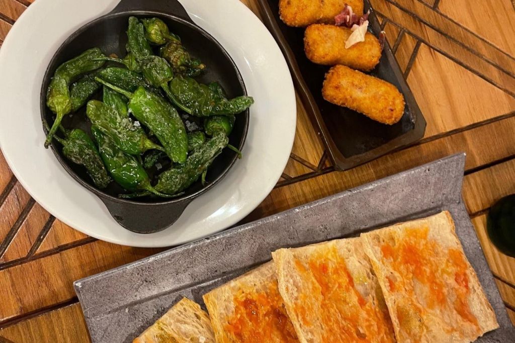 고추, 크로켓, 토마토 스프레드와 함께 구운 빵의 요리가 담긴 테이블입니다.