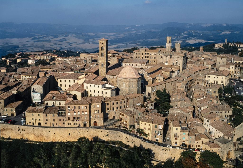 갈색 지붕의 건물, 높은 종탑, 주변 언덕을 배경으로 한 구시가지의 공중 풍경.