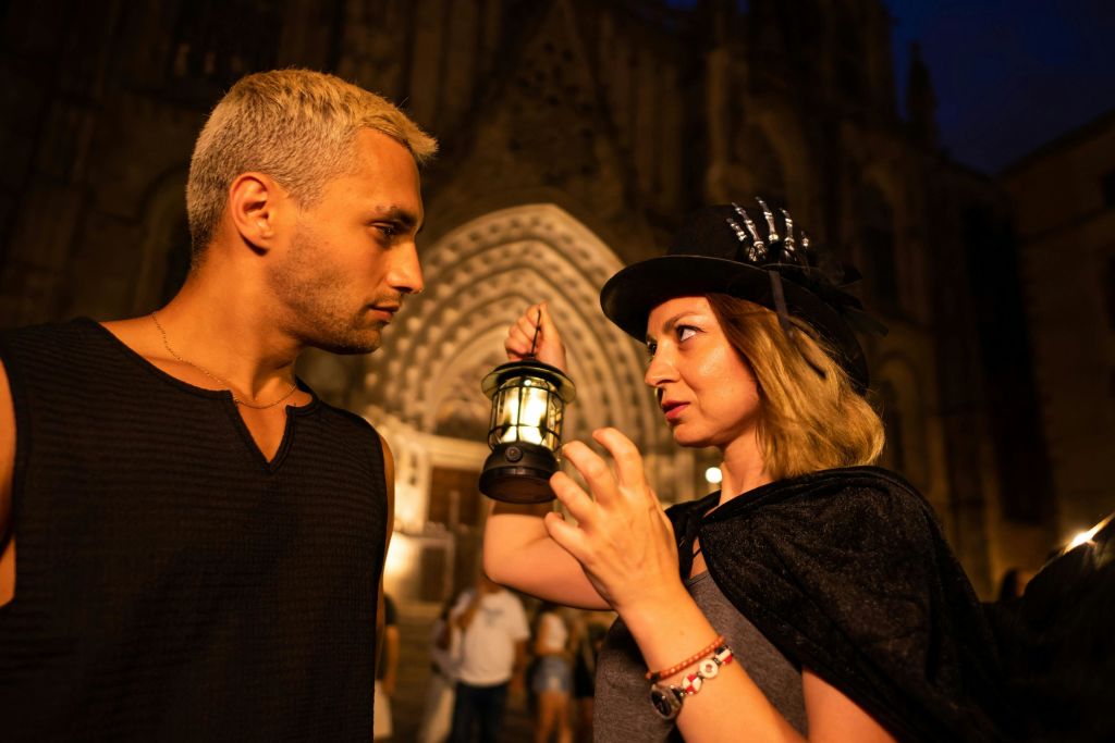 두 사람이 마주보고 있는데, 한 사람은 랜턴을 들고 있습니다. 그들은 밤에 화려한 조명으로 장식된 건물 앞에 서 있습니다.