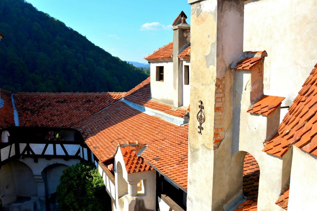 맑고 푸른 하늘 아래 산과 나무를 배경으로 한 오래된 건물의 붉은 기와 지붕.