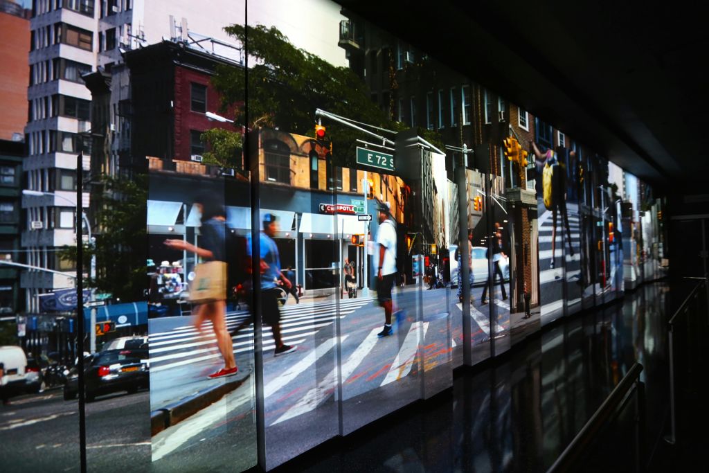 번잡한 도심의 교차로를 흐릿한 움직임으로 걷고 있는 사람들. 횡단보도와 신호등이 보입니다.