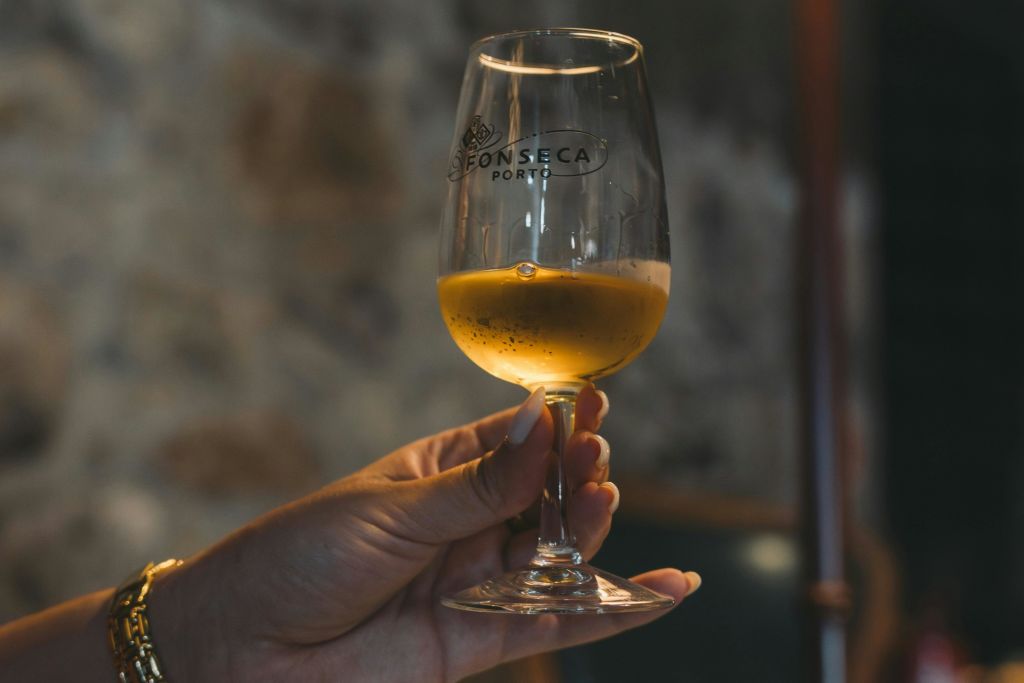 황금빛 액체가 담긴 와인잔을 들고 있는 손에는 "Fonseca Porto" 로고가 배경으로 새겨져 있습니다.