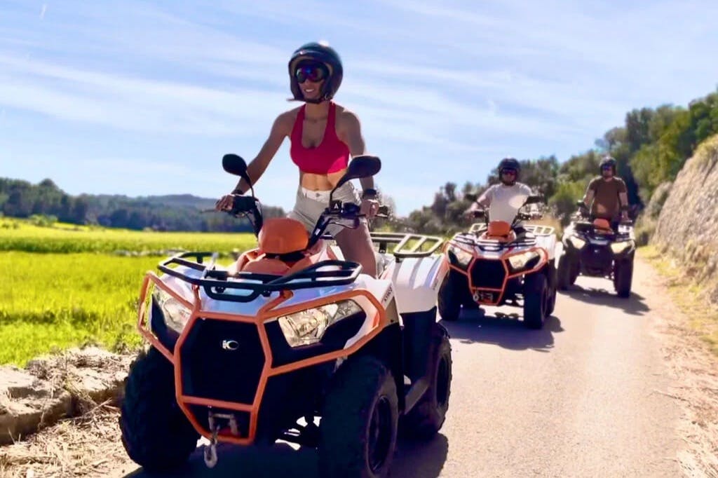 화창한 날 푸른 하늘과 푸른 들판을 배경으로 전지형 차량을 타고 있는 두 사람.