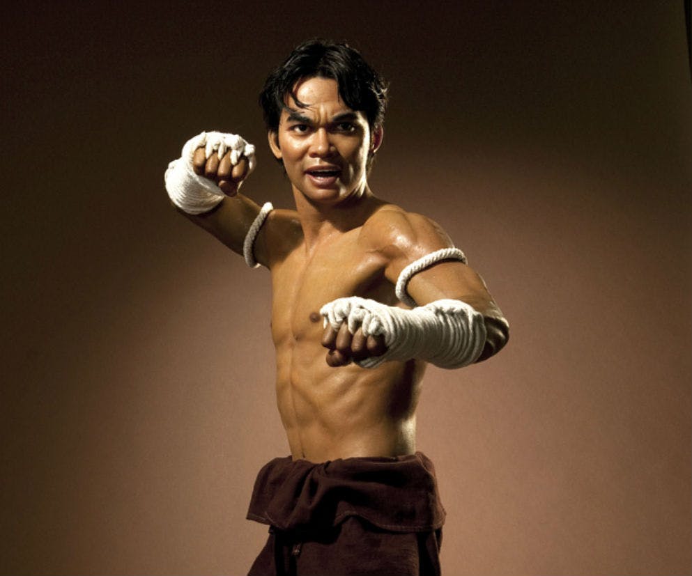 팔과 손을 감싸는 셔츠 없는 사람이 평범한 갈색 배경에 맞서 싸우는 자세로 포즈를 취합니다.