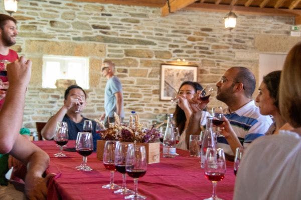 돌담과 소박한 인테리어가 돋보이는 방에서 빨간 식탁보가 놓인 테이블에 둘러앉아 와인잔을 즐기고 있는 사람들.