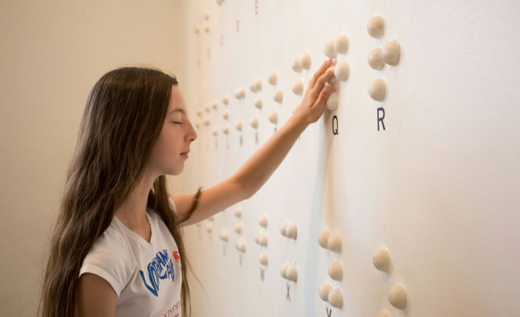 한 소녀가 점자를 느끼려고 합니다.