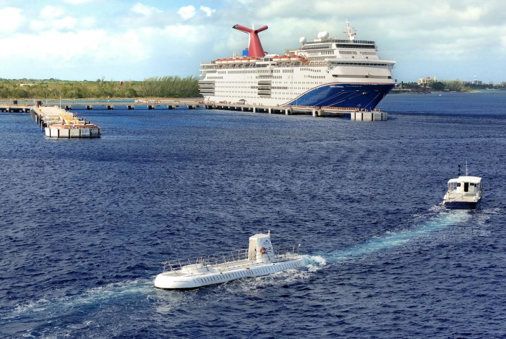 대형 유람선이 부두에 정박해 있으며, 근처에 작은 흰색 잠수함이 있습니다.