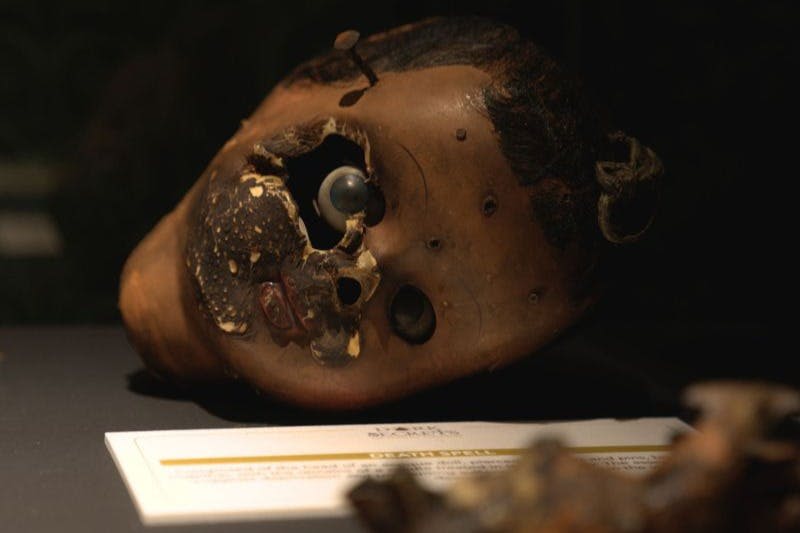 아래 라벨이 표시된 표면에 표시된 눈과 부패가 누락된 손상된 인형 머리.