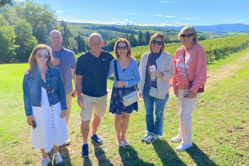 아름다운 시골 풍경을 배경으로 잔디가 우거진 야외에서 여섯 명이 함께 서 있습니다.