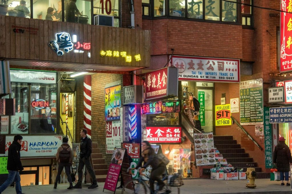 레스토랑과 상점, 걷는 사람들, 자전거 타는 사람을 위한 다양한 조명 표지판이 있는 번화한 거리 풍경.