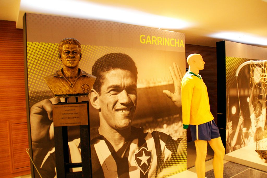 축구 선수 개린차의 흉상과 대형 사진, 전시물 뒤 벽에 그의 이름이 굵게 표시되어 있습니다.