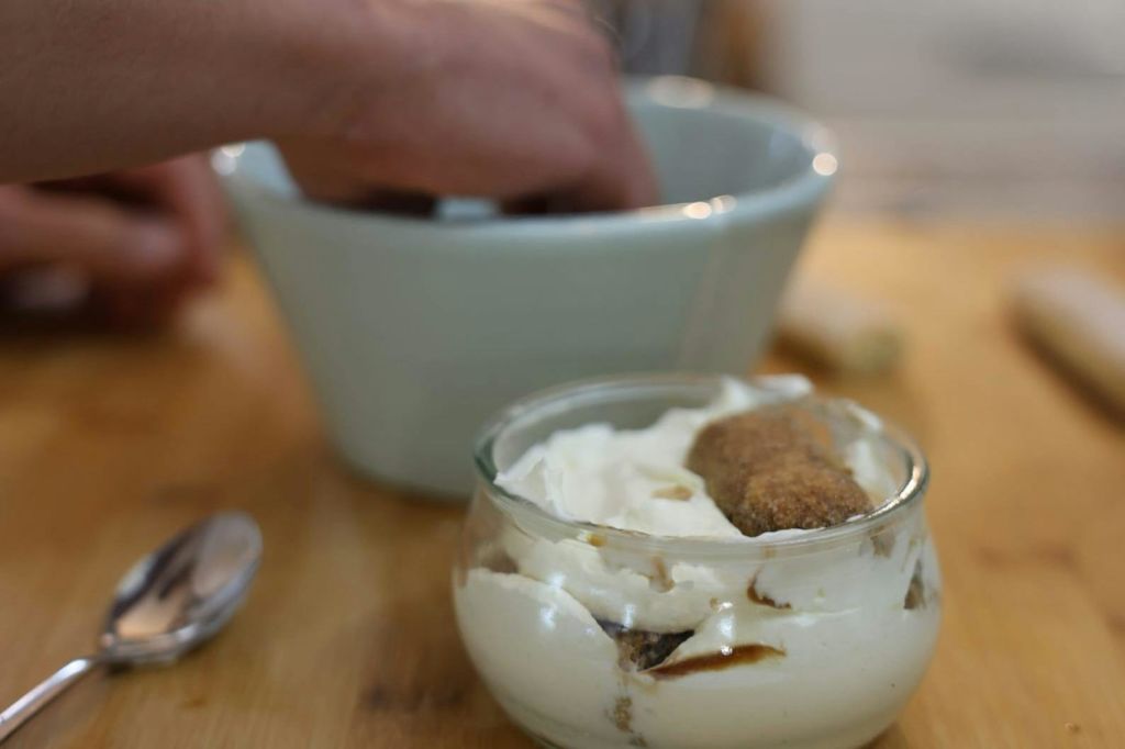 티라미수를 만드는 동안 큰 그릇에 손을 담그면 크림과 레이디핑거 비스킷이 겹겹이 담긴 유리 접시가 전면에 나옵니다.