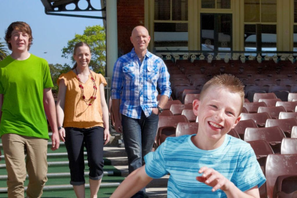 건물과 좌석 공간 근처에 있는 야외에서 4명으로 구성된 그룹으로, 3명은 걷고 1명은 전경에서 달립니다.