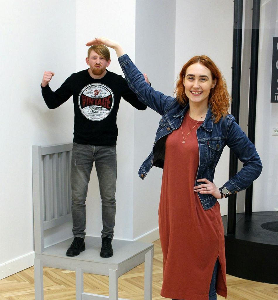 한 여성이 전경에 서서 커다란 의자에 앉아 있는 남성의 머리를 쓰다듬고 있습니다.