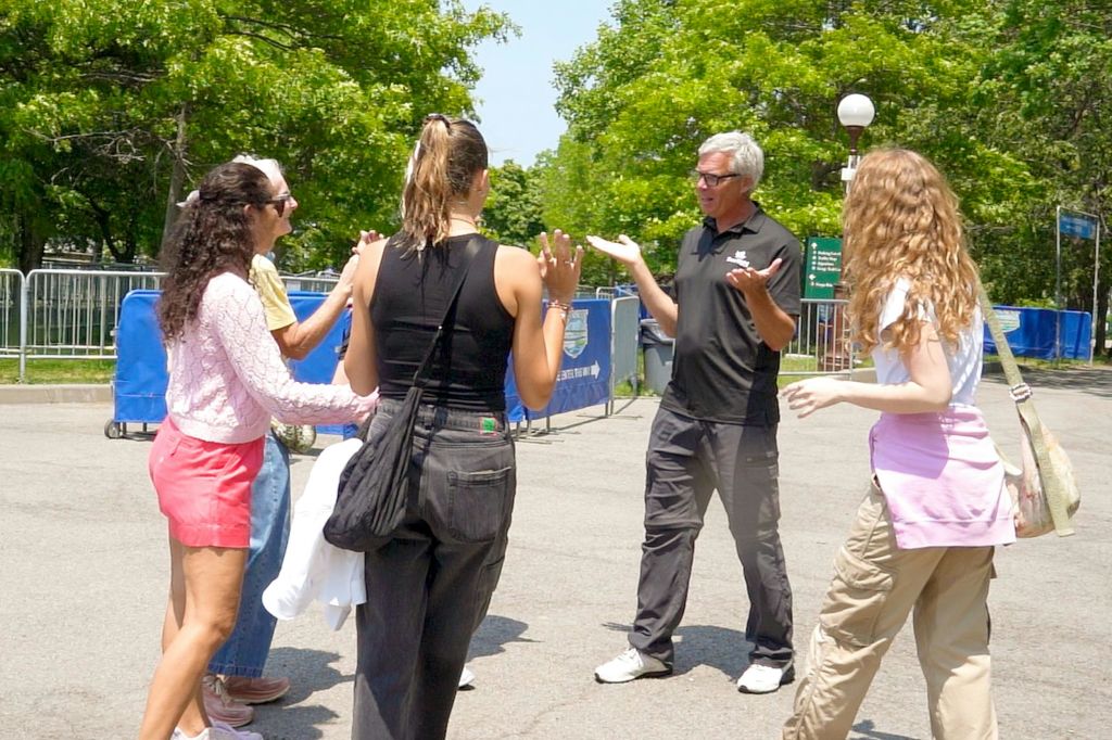 화창한 날, 나무와 가로등을 배경으로 한 남녀 세 명이 야외에서 대화를 나누고 있습니다.