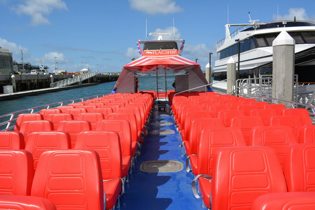 파란 하늘 아래 다른 보트 옆에 '플래그십' 이라고 표시된 보트 갑판의 빨간색 좌석이 줄지어 정박해 있습니다.