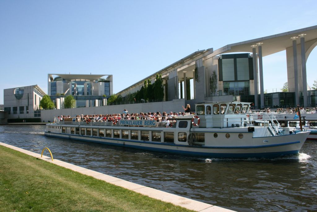 '프렌츠라우어 베르크' 라는 이름의 투어 보트는 맑고 푸른 하늘 아래 현대적인 건물 앞의 강을 따라 사람들이 가득합니다.