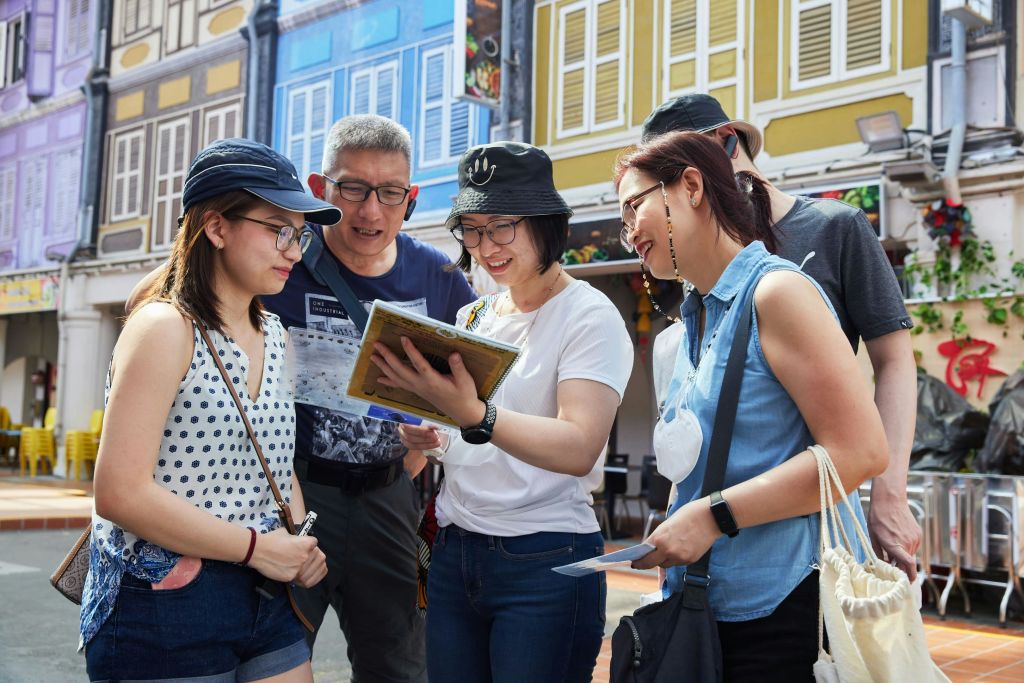다채로운 색상의 건물을 배경으로 지도를 바라보며 야외에 서 있는 네 명의 사람들.